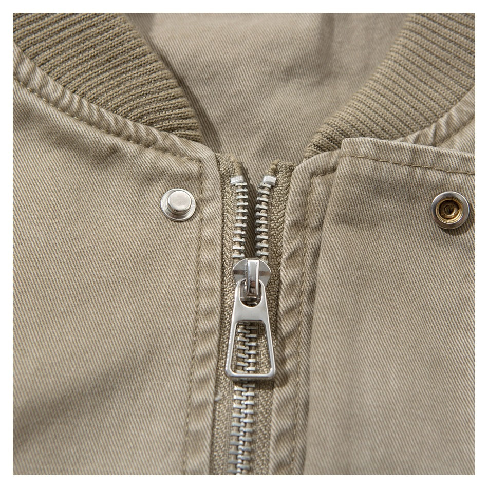 Close-up of a beige jacket's ribbed collar, central metal zipper, and snap fasteners.