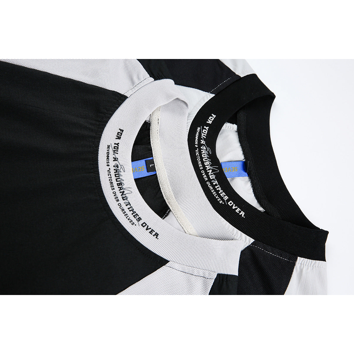 Close-up of the two T-shirts’ ribbed crew necklines, printed inner neck bands, and shoulder panels.