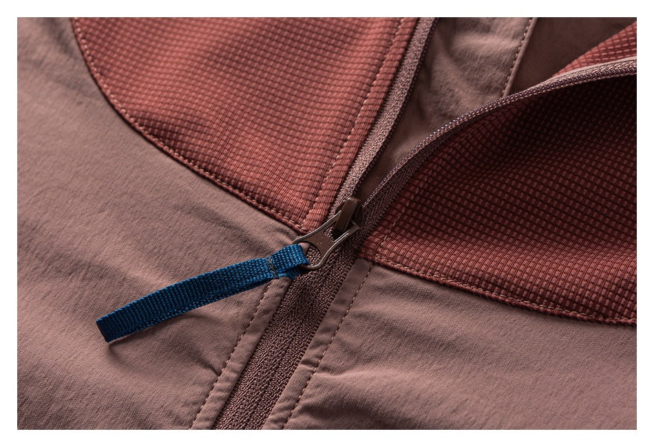Close-up of a mauve garment zipper with a blue pull tab beside textured reddish panels.