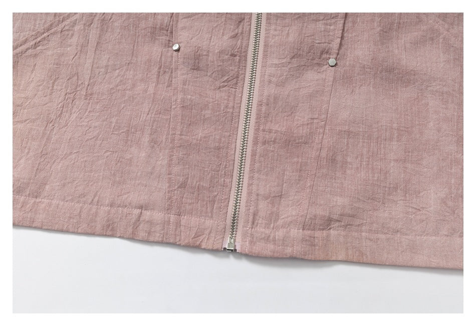 Close-up of the dusty rose garment's front zipper, stitched panels, and small pale buttons.