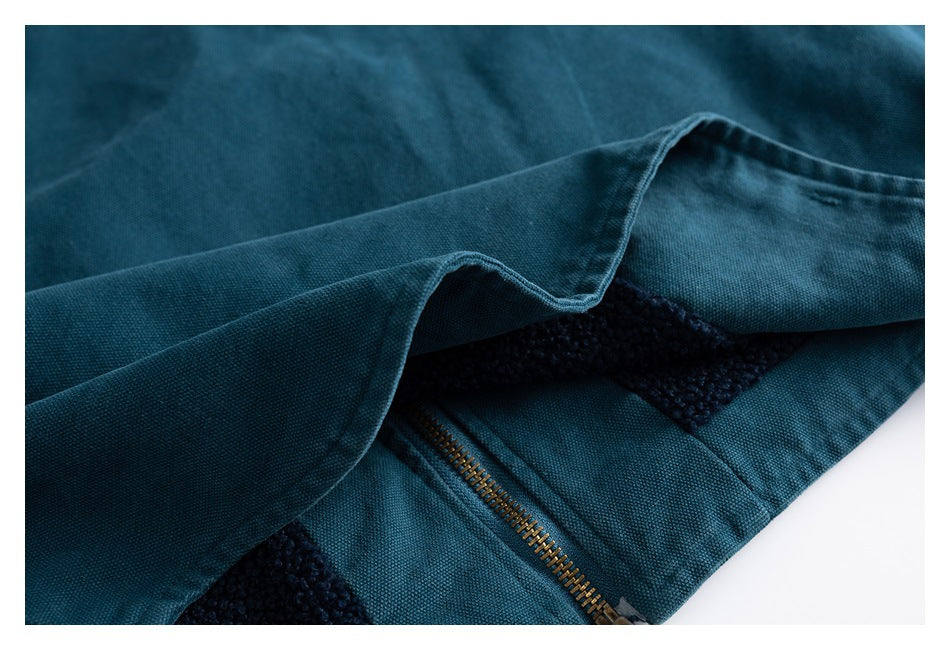 Close-up of teal garment folds with a brass-colored zipper and dark textured panels.