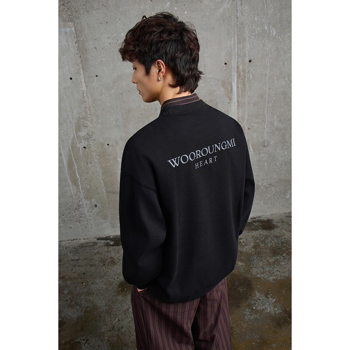 Model wearing a black oversized sweatshirt, shown from behind with white WOOROUNGMI HEART lettering.