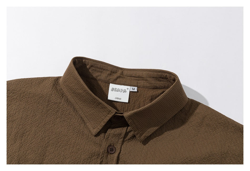Close-up of a brown textured shirt collar, top button, and neck label.
