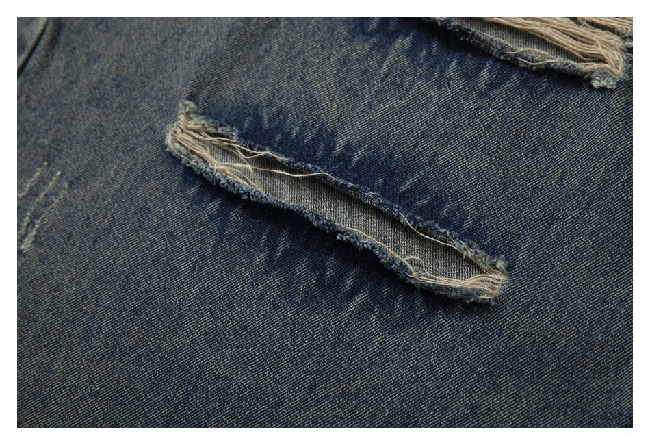 Close-up of a narrow horizontal slit with frayed edges in faded blue denim.