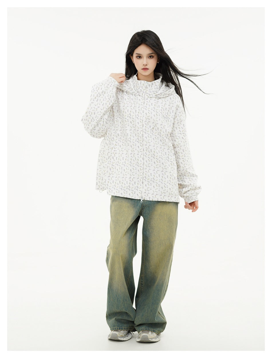 Full-length model wearing a white floral-print hooded zip jacket with loose blue-green jeans.