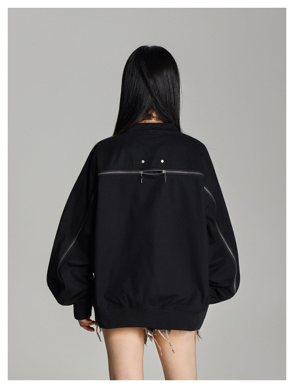 Back view of a model wearing a black oversized jacket with zippered sleeves and a horizontal back zipper.