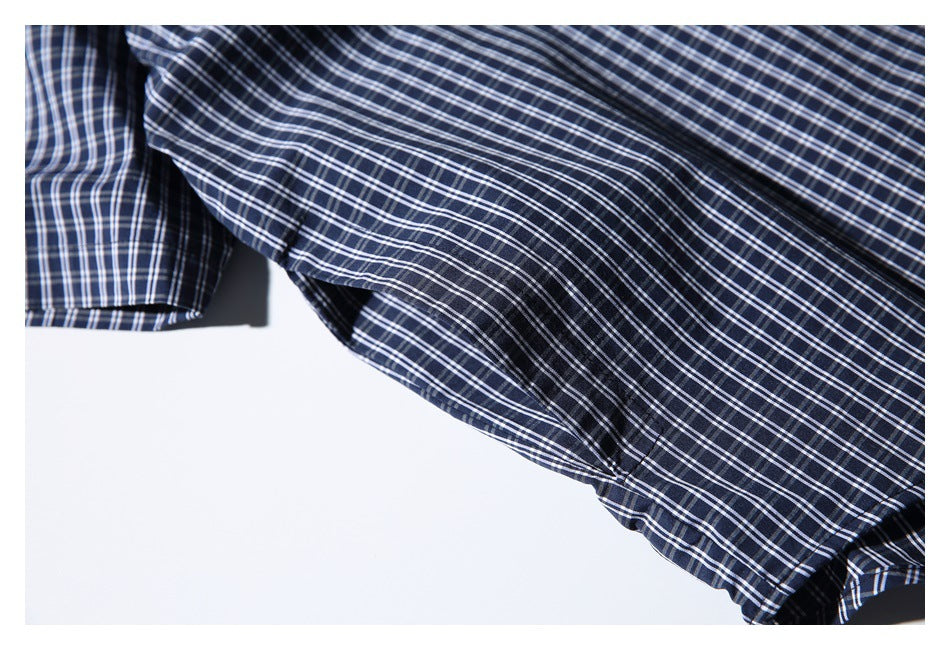 Close-up of the navy-and-white plaid shirt fabric and a curved garment edge.