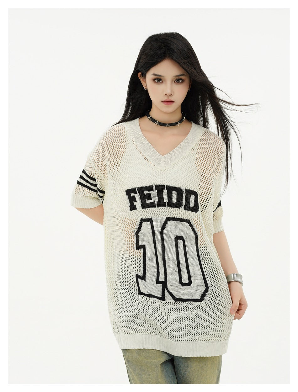 Close view of a model wearing an ivory open-knit tunic with black sleeve stripes and FEIDD 10 lettering.