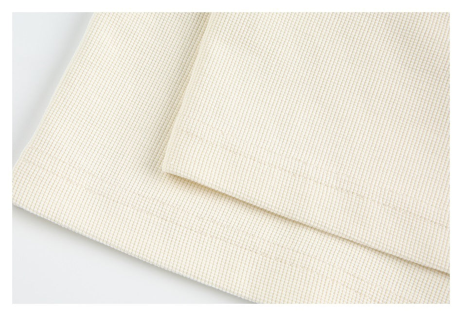 Close-up of overlapping edges and stitching on the cream textured garment.