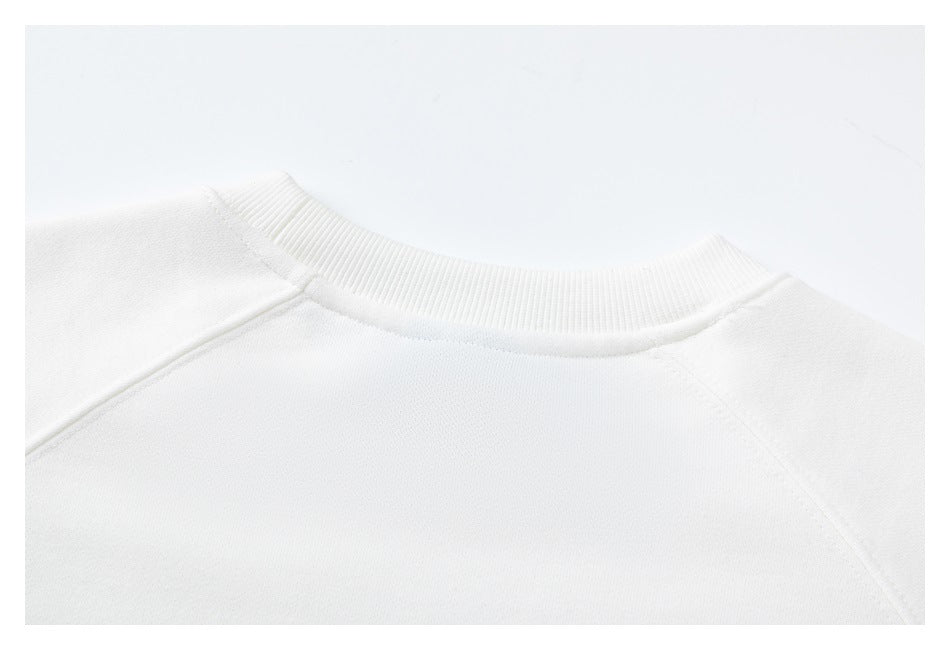 Close-up of the white sweatshirt's ribbed crew neck and raglan shoulder seams.