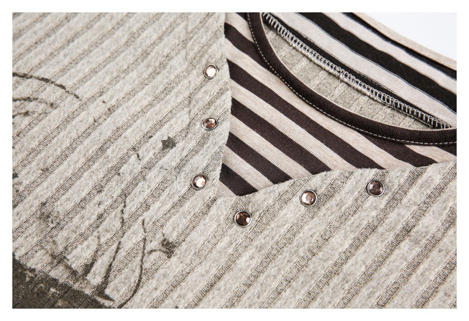 Close-up of a gray striped top showing its dark striped neckline and decorative metal studs.