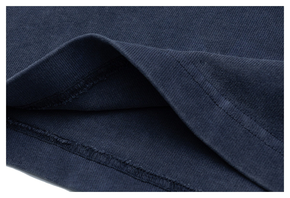 Close-up of the navy T-shirt's folded bottom hem and stitching.