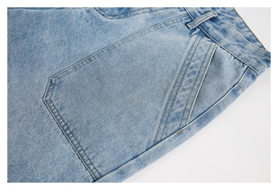 Close-up of a rear patch pocket and double-stitched seams on light blue denim shorts.