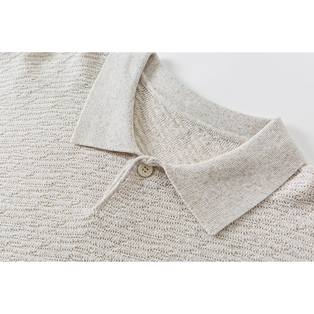 Close-up of a cream knit pullover's pointed collar and single button.
