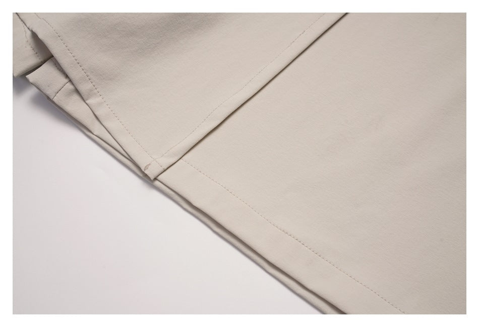 Close-up of intersecting stitched seams and a folded edge on light beige fabric.