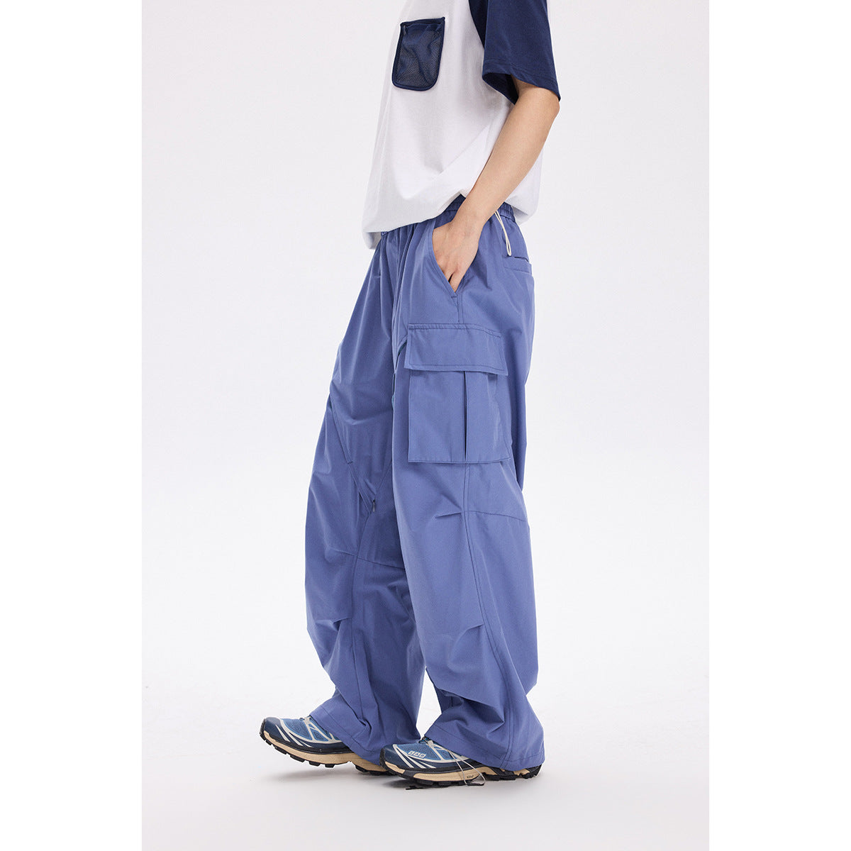 Model wearing loose periwinkle cargo pants with large flap pockets and a white-and-navy shirt.