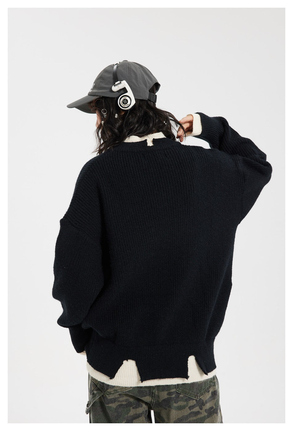 Rear view of a model wearing a black ribbed sweater with cream collar, cuffs, and contrast hem.