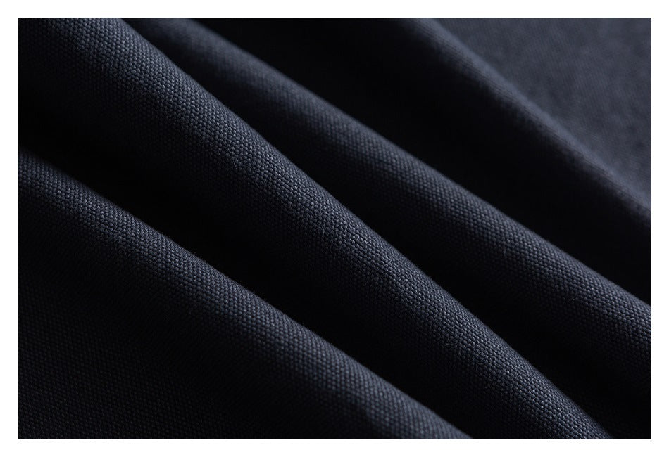 Extreme close-up of dark fabric draped in folds, showing its small woven surface texture.