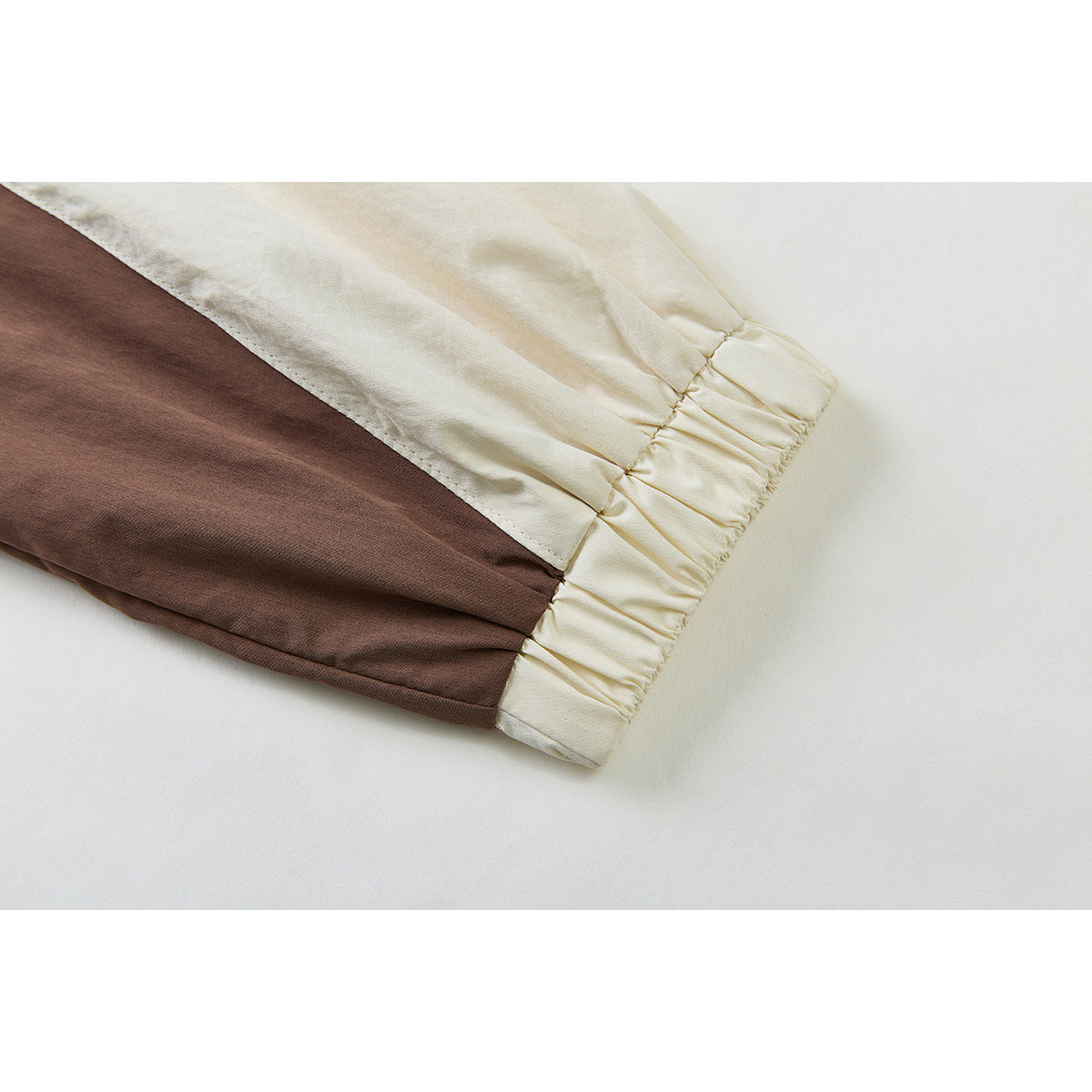 Close-up of a cream and brown jacket sleeve ending in a gathered cream cuff.