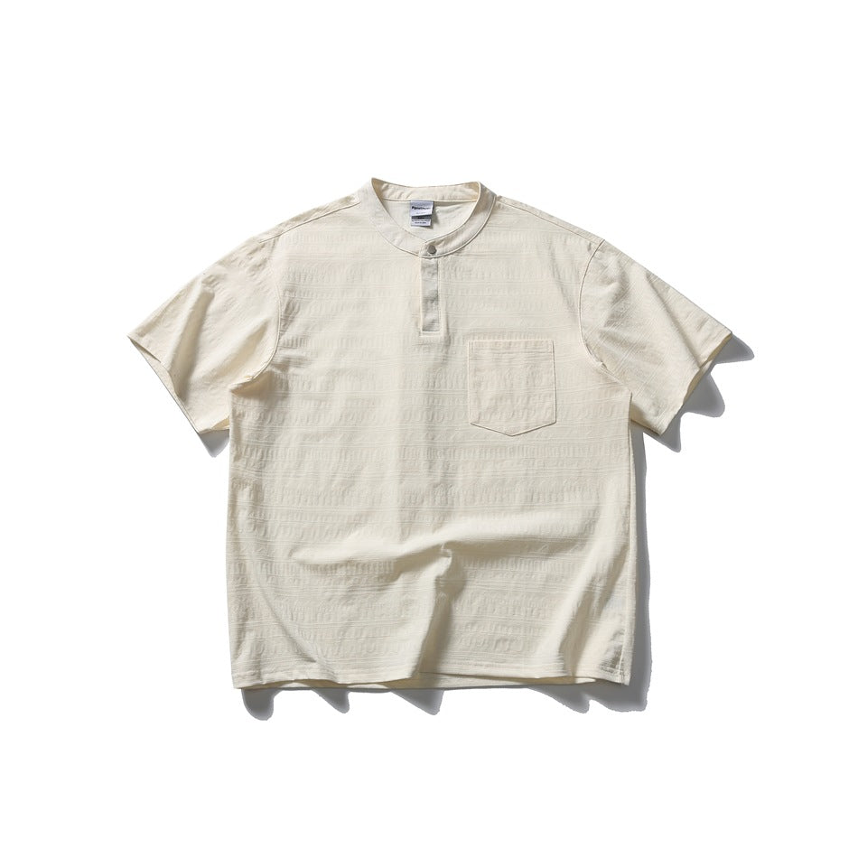Cream white short-sleeve Henley-style top with band collar, snap placket, chest pocket and textured pattern, flat lay