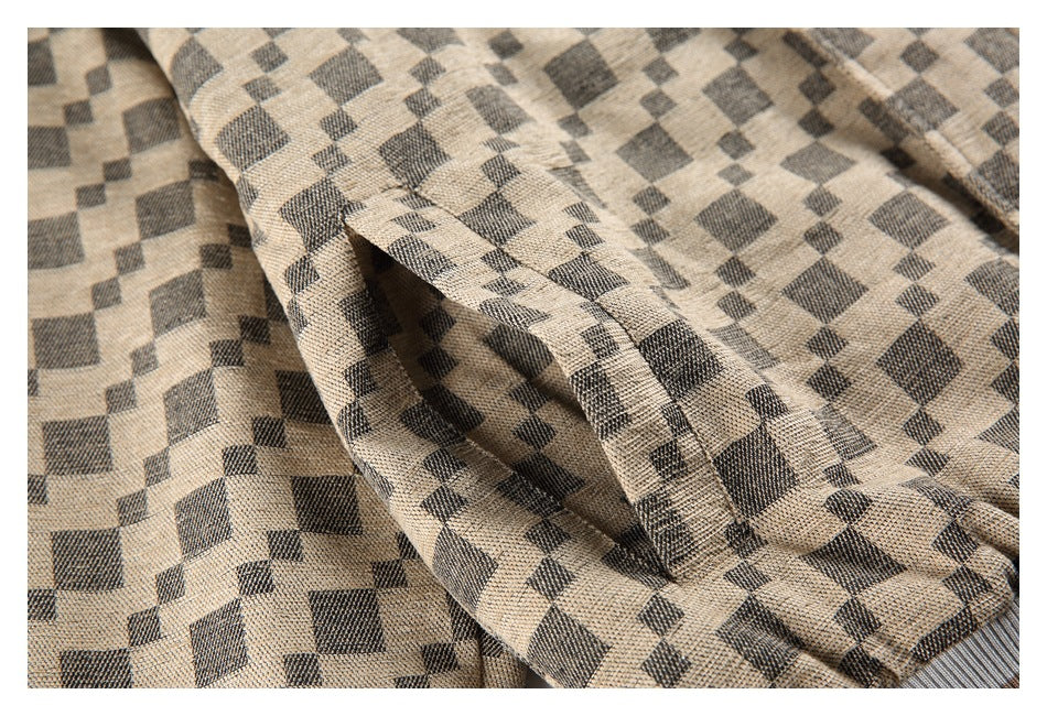 Close-up of a pocket and stitching on a beige jacket with a charcoal check pattern.