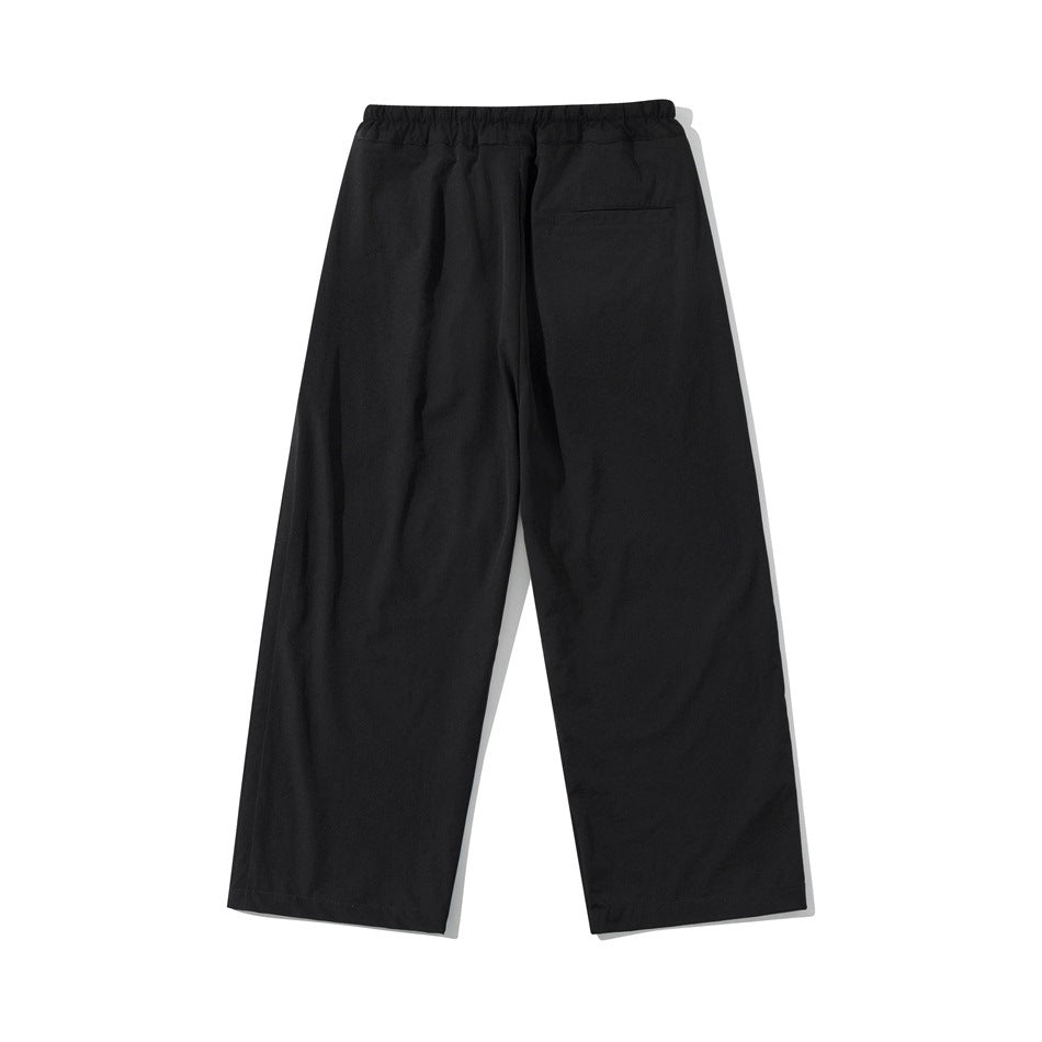 Black wide-leg pants shown from the back, with an elastic waistband and a single welt pocket.