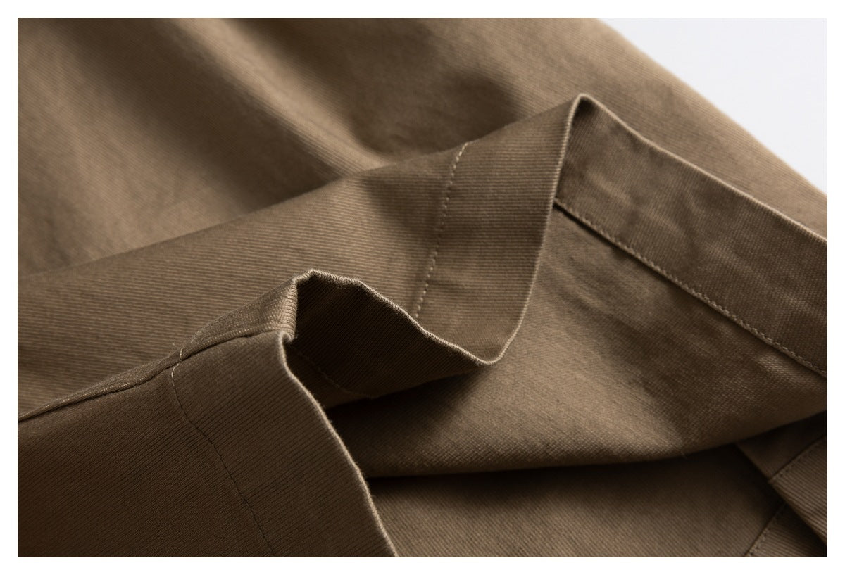 Close-up of brown trousers showing folded fabric, seams and stitching.