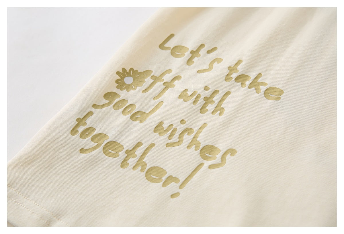 Close-up of tan English lettering and a flower printed on cream fabric.