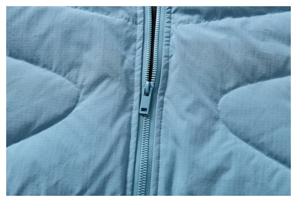 Close-up of the light blue jacket's front zipper and curved stitched panels.