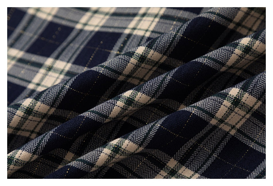Close-up of navy, cream, and muted green plaid fabric arranged in soft folds.