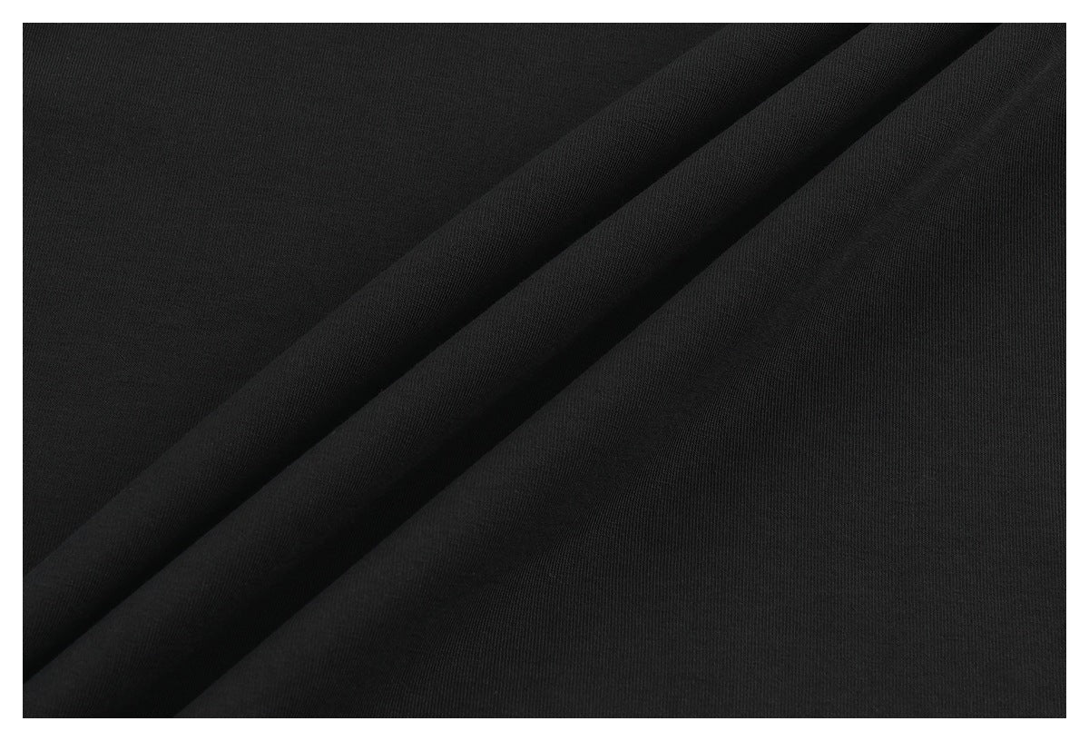 Close-up of smooth black fabric arranged in broad diagonal folds.