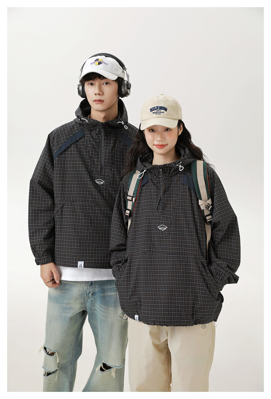 Man and woman model matching black checked hooded pullover jackets with front pockets and drawstrings.