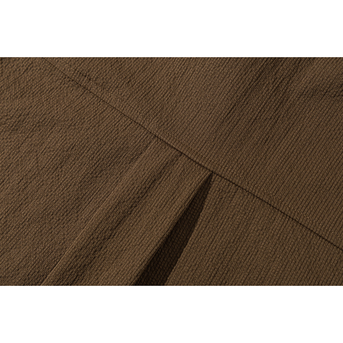 Extreme close-up of the brown shirt's fine textured fabric and seam stitching.