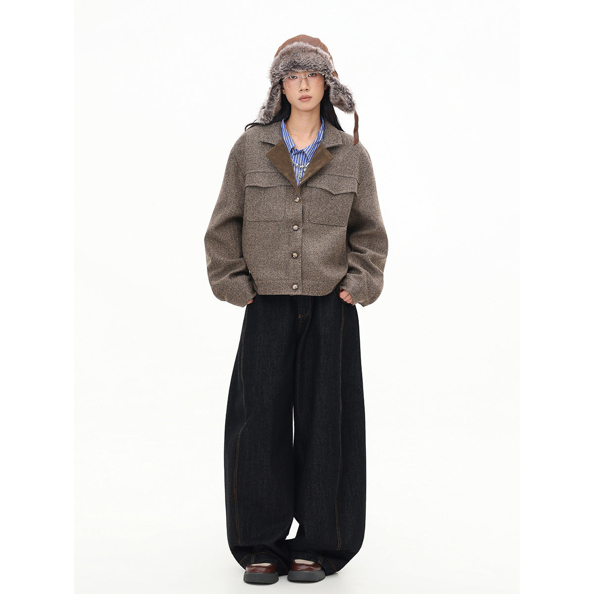 Full-length view of a model in a mottled brown button-front jacket, fur-trimmed hat, and wide-leg black jeans.