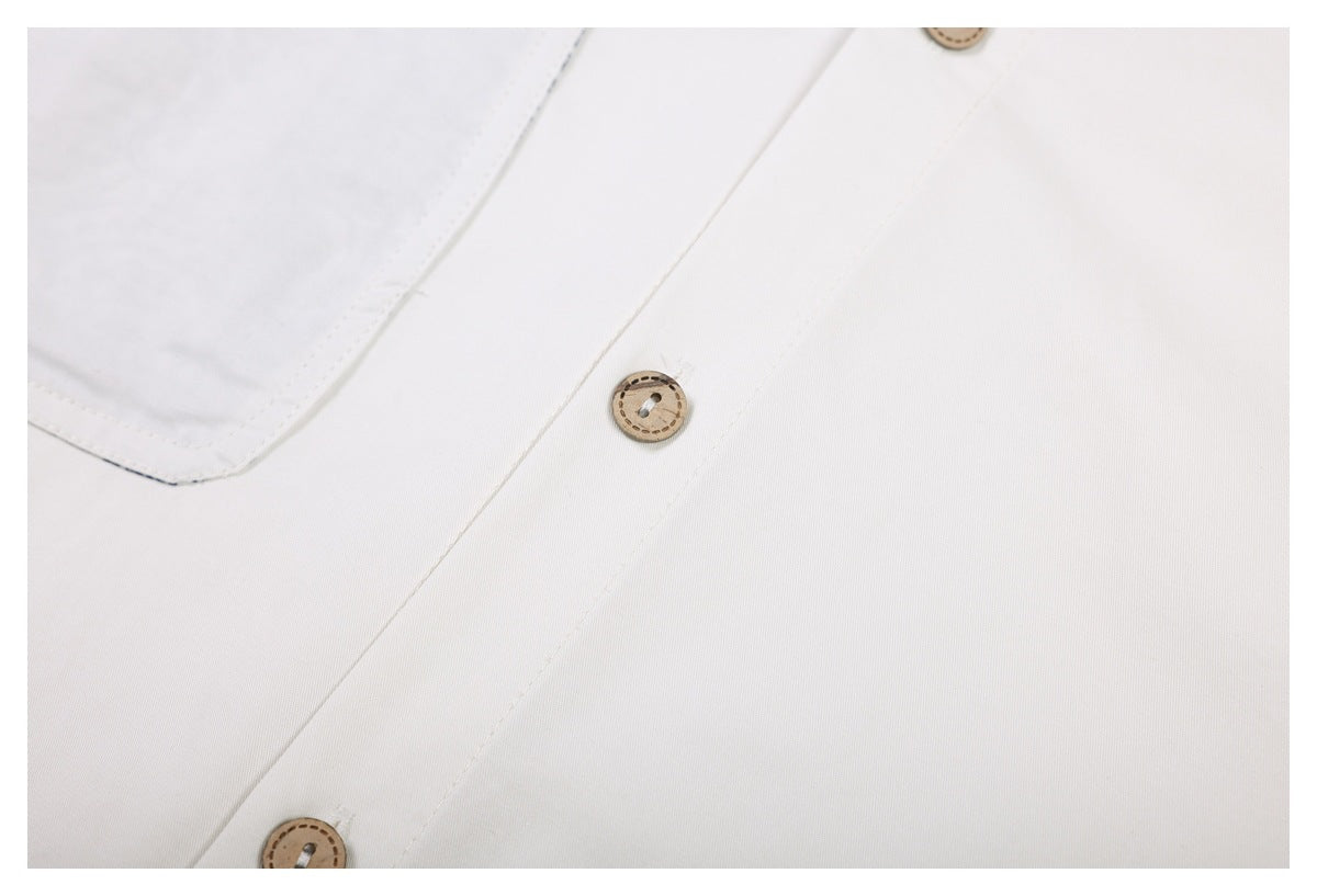 Close-up of a white garment's placket with tan buttons and visible stitching.