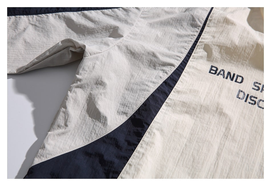 Close-up of the pullover's ivory sleeve and body with a curved navy color-block panel.