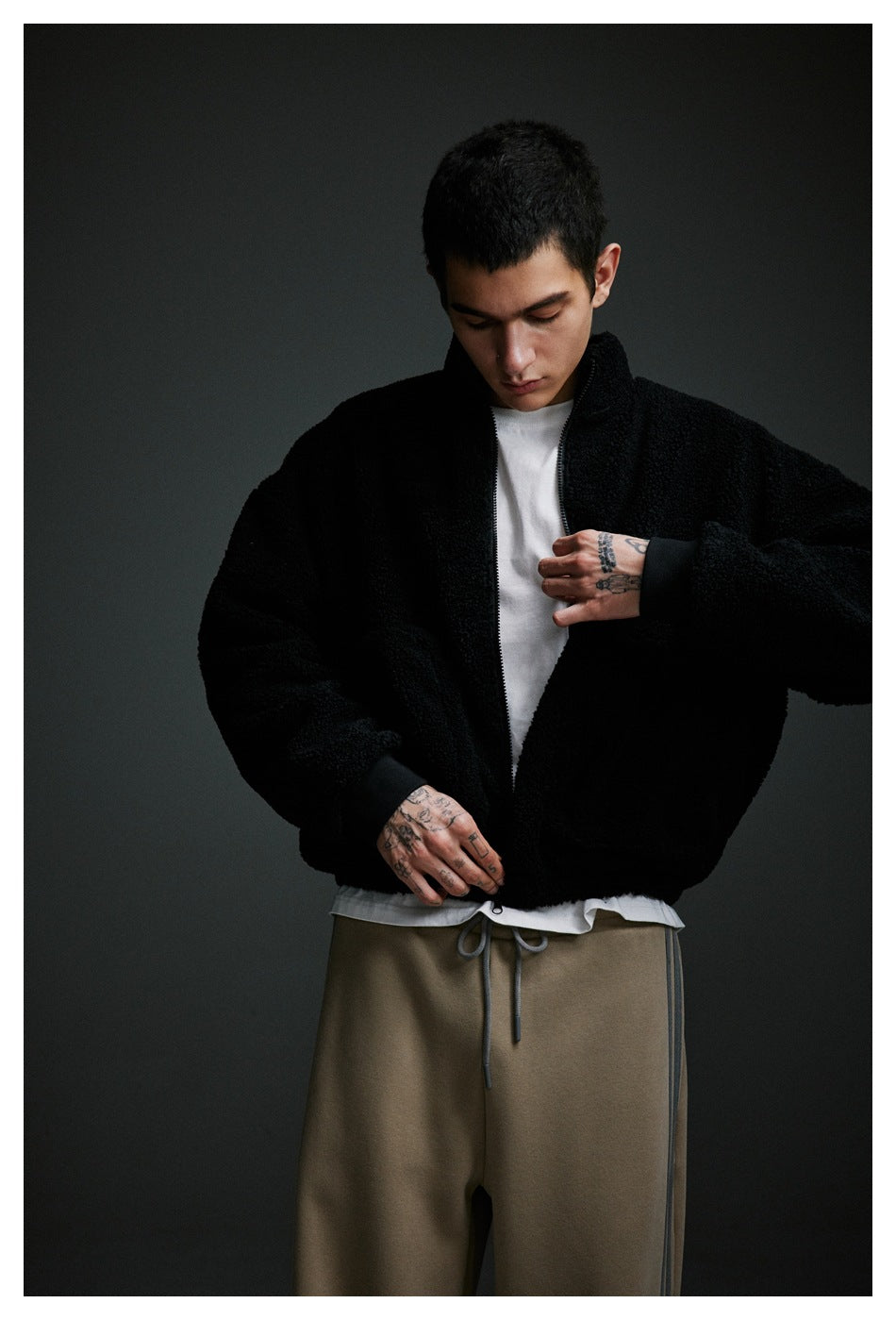 Close view of a model wearing a black zip-up fleece jacket with a high collar and ribbed cuffs.