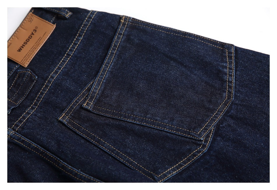 Close-up of a large back pocket on dark indigo jeans, with golden contrast stitching and a partial leather label.
