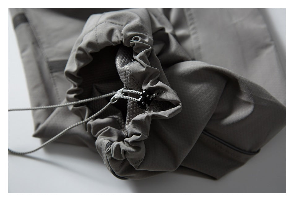 Close-up of gray trousers with a gathered drawcord opening, cord lock, and textured inner panel.
