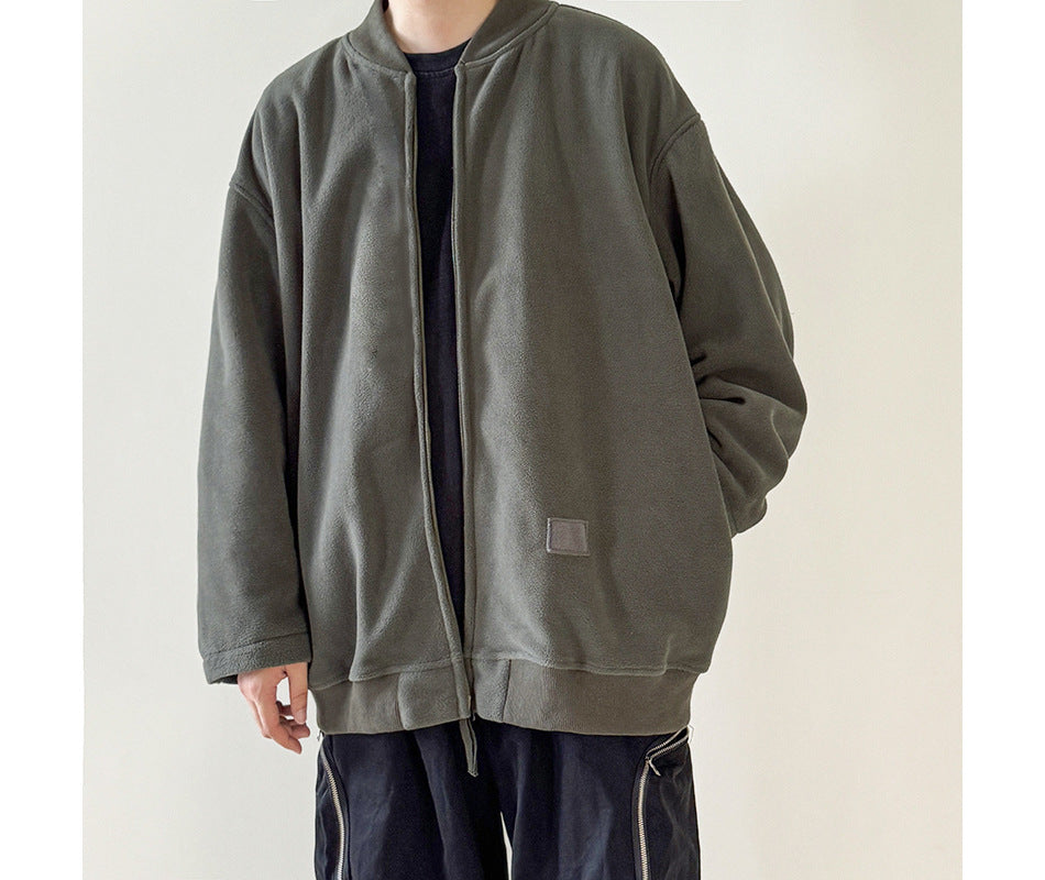 Person wearing an oversized gray-green zip fleece-like jacket over a dark top and dark pants with zipper details