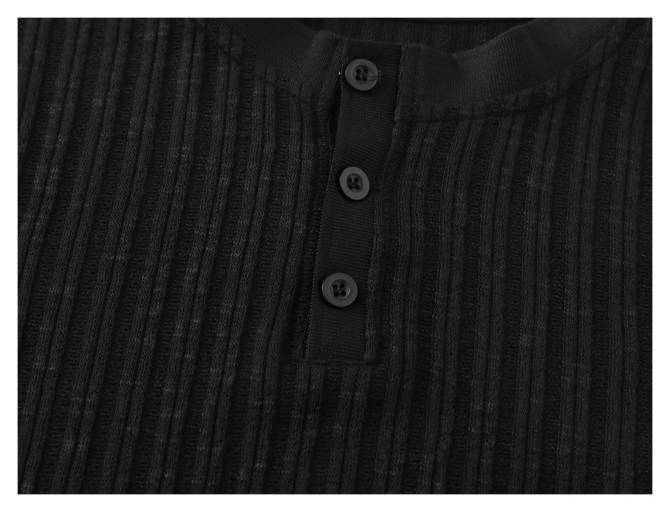 Close-up of the black shirt's vertical ribbed texture and three-button placket.