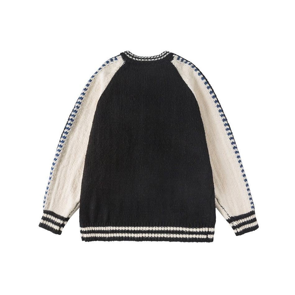 Back of a black knit cardigan with cream raglan sleeves, navy patterned sleeve edges, and striped cuffs and hem.