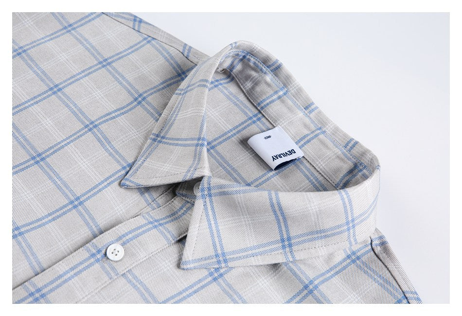 Close-up of a gray-and-blue plaid shirt collar, button, and small neck label.