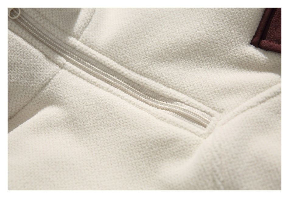 Close-up of a light-colored zipper across cream textured fabric, with part of a brown trim visible.