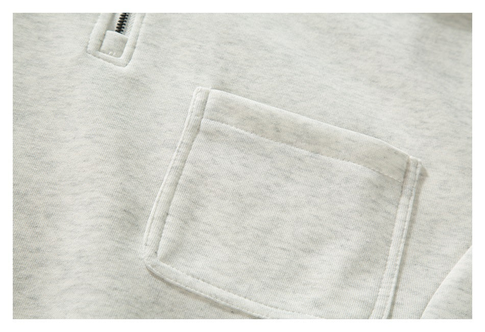 Close-up of a square patch pocket on a light gray heathered sweatshirt.