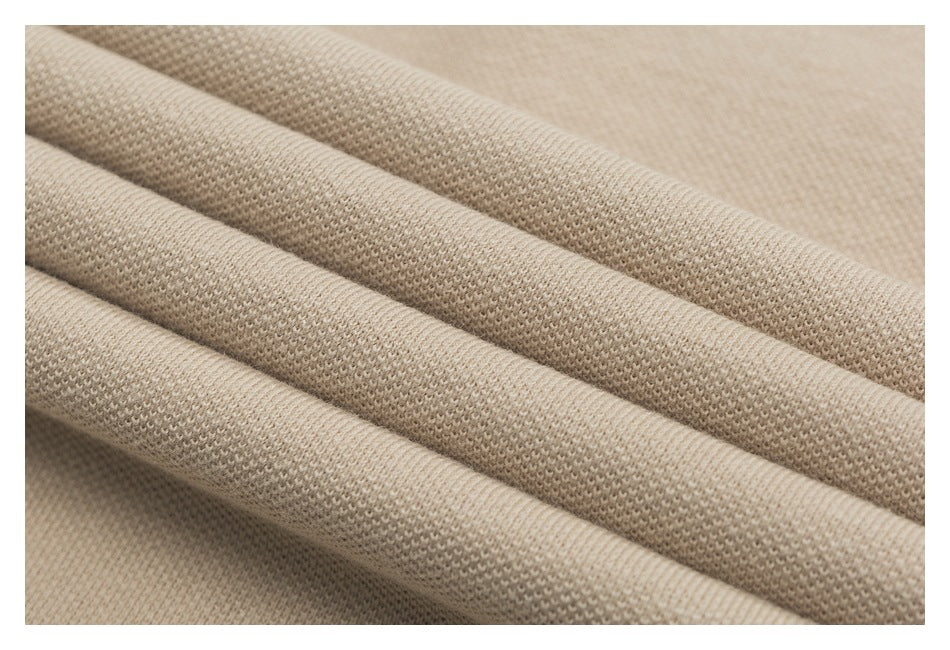 Close-up of beige textured polo fabric draped in soft folds.