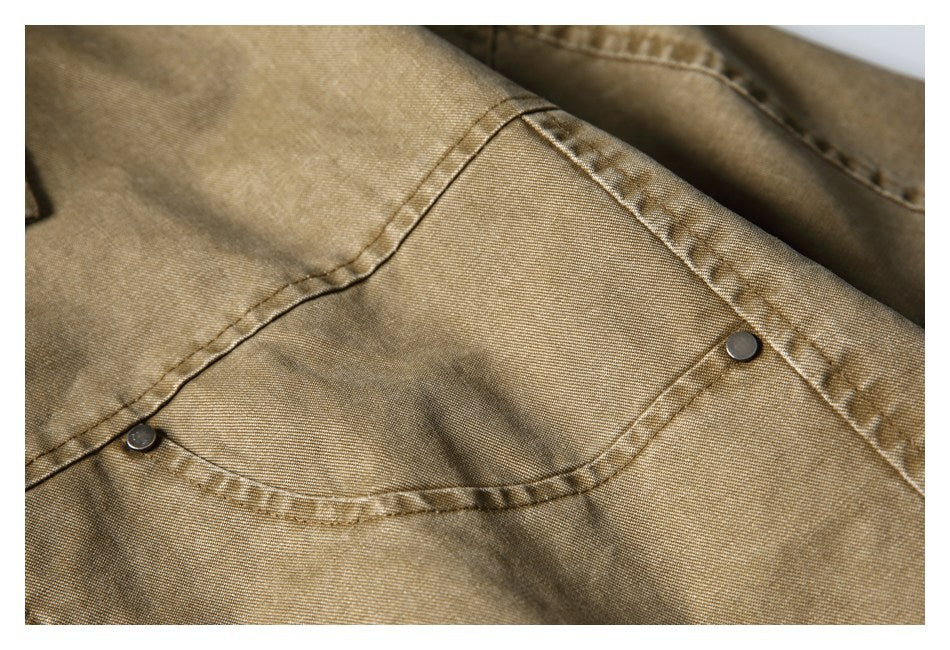 Close-up of a curved flap pocket with two dark snap buttons on a tan-brown jacket.