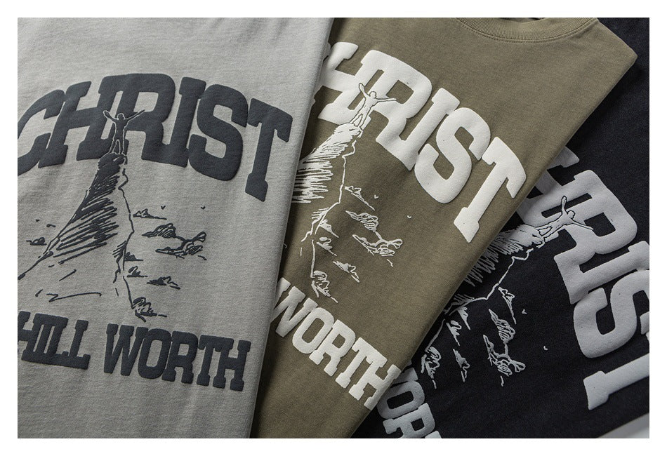 Three folded graphic T-shirts in gray, olive, and black, each with a climber illustration and large lettering.