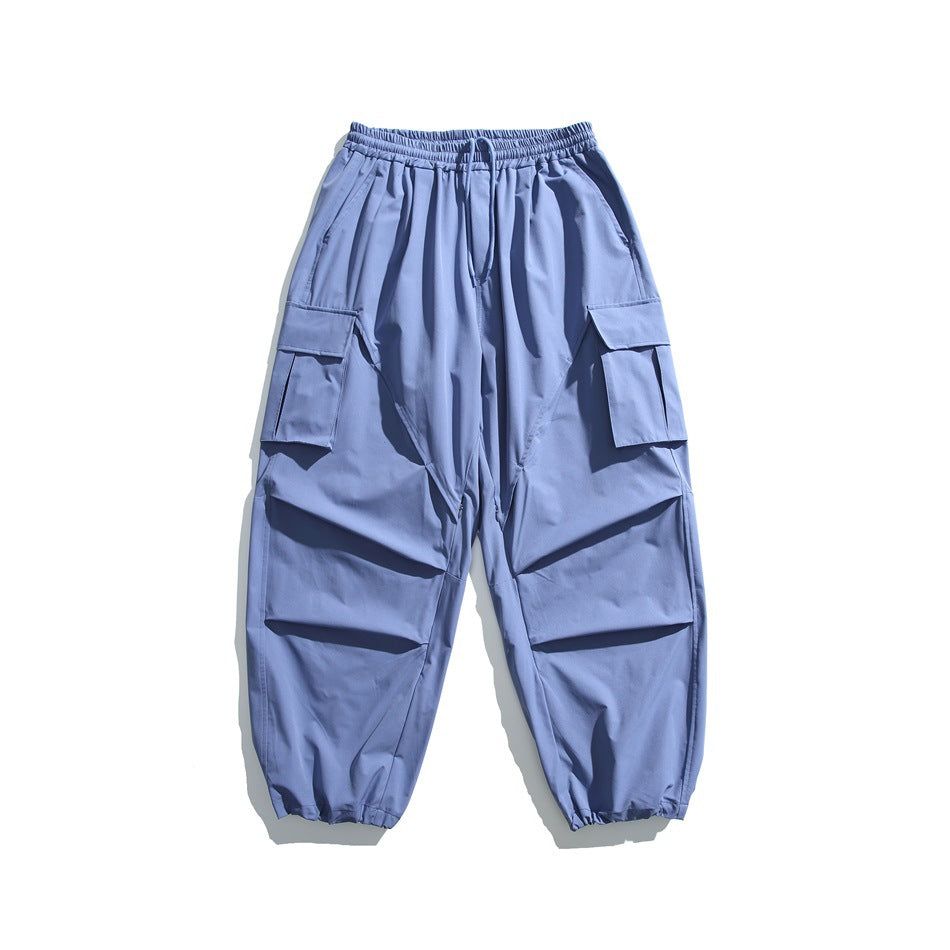 Blue wide-leg cargo pants with drawstring waist, flap thigh pockets and gathered hems, flat lay
