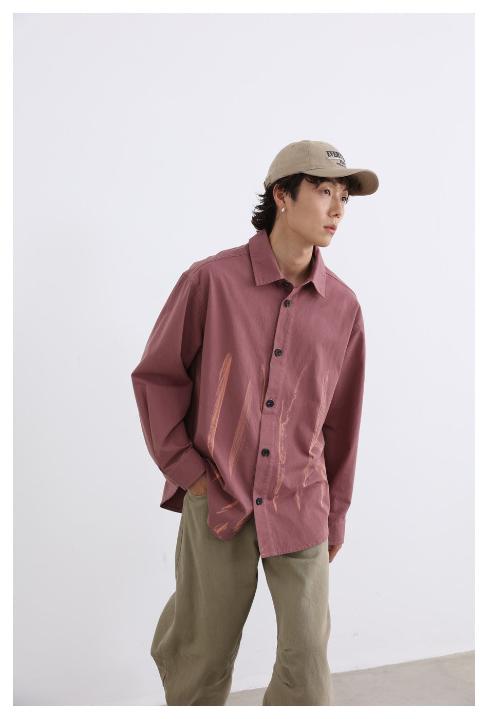 Model wearing a dusty rose button-up shirt with tan brushstroke graphics and khaki trousers, shown from the front.